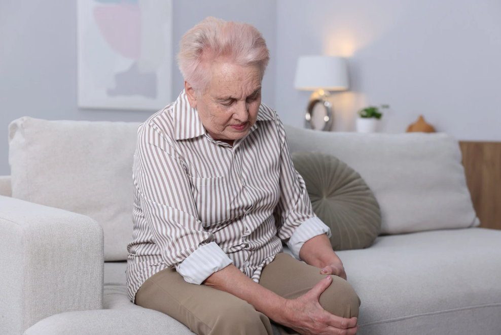 Senhora com a mão no joelho sentindo dor de artrose, condição que pode melhorar com construção de músculos e fortalecimento muscular